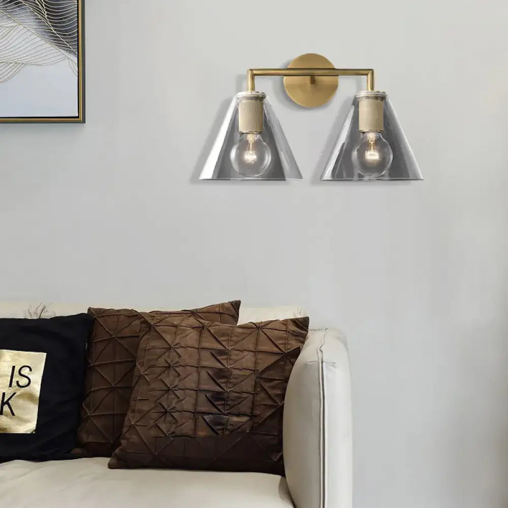Brass-finished modern wall light with two triangular glass shades and direct wired electric sockets for bedroom use