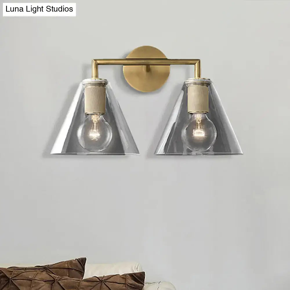 Brass-finished modern wall light with two clear glass cone shades and direct wired electric exposed bulb sockets