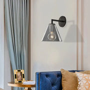 Modern black metal wall light with clear glass conical shade and exposed bulb, direct wired electric for bedroom use