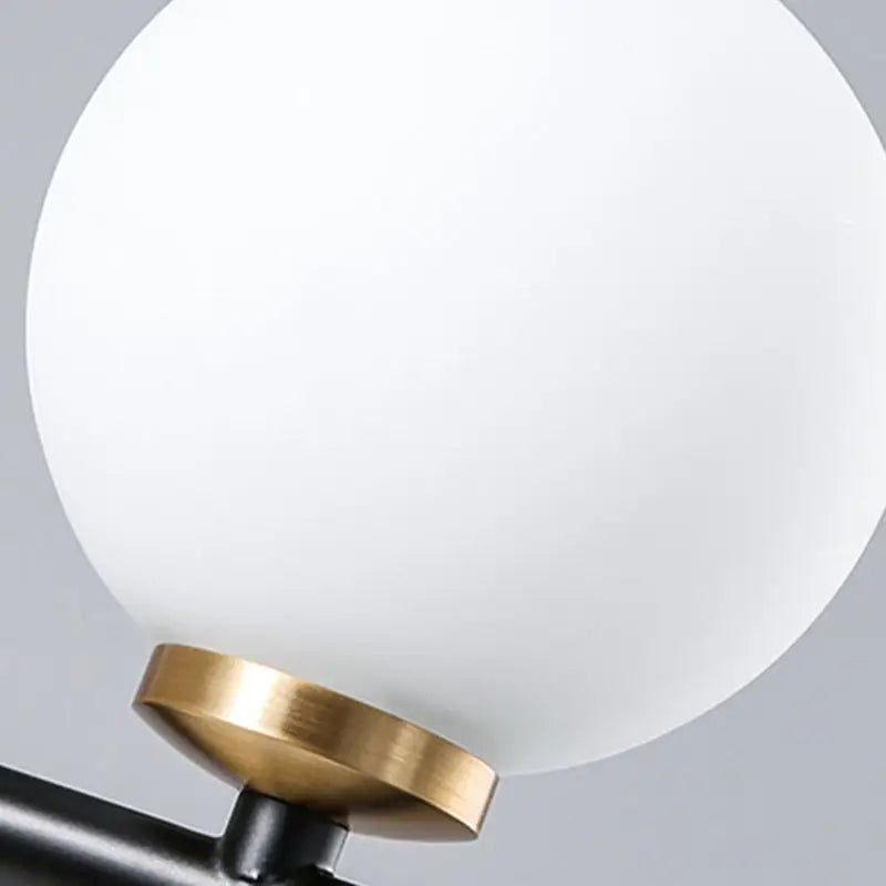 Modern black and brass linear chandelier featuring a spherical white glass frosted globe lampshade for dining room