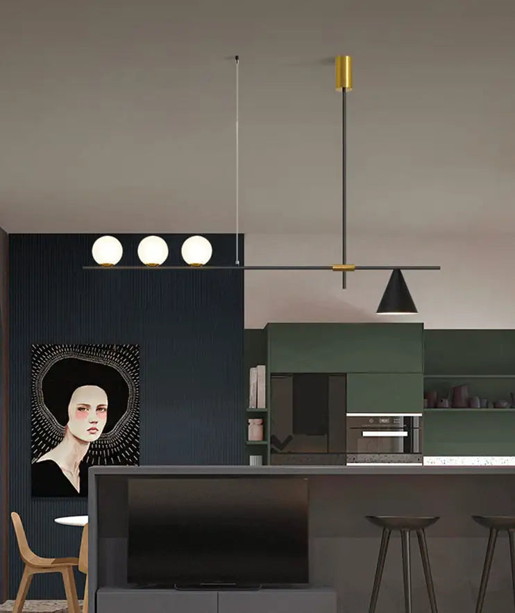 Modern black and brass linear chandelier featuring three spherical white glass bulbs and slender gold-toned rods