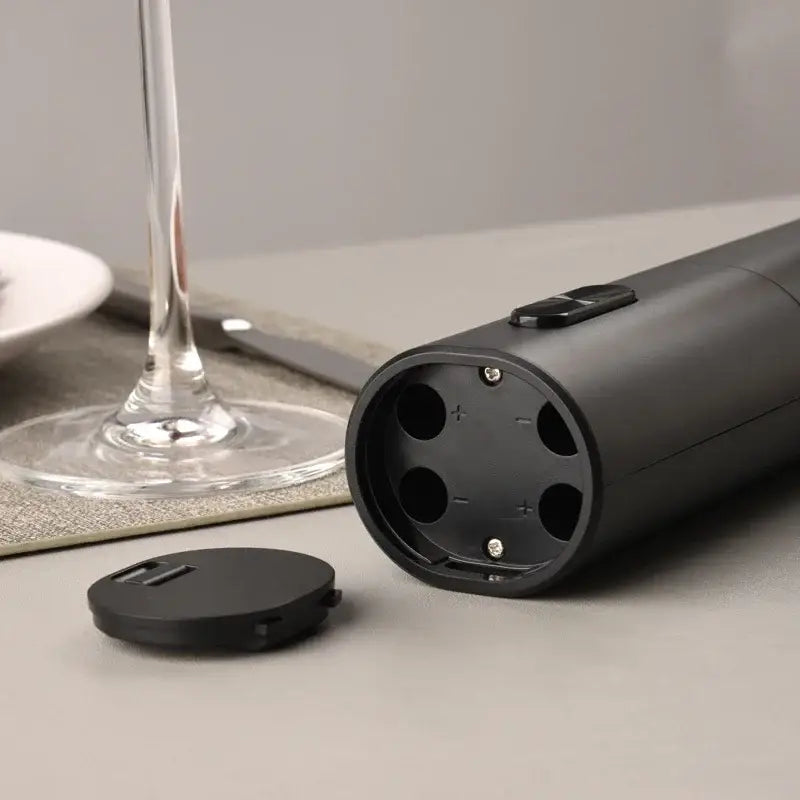 Modern black brushed metal electric wine opener showing battery compartment with removable cap for kitchen use