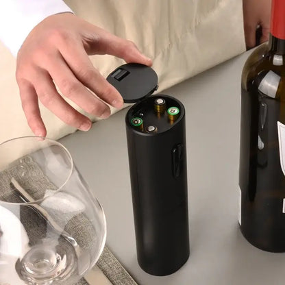 Modern black brushed metal electric wine opener with hinged lid and visible battery compartments for easy use