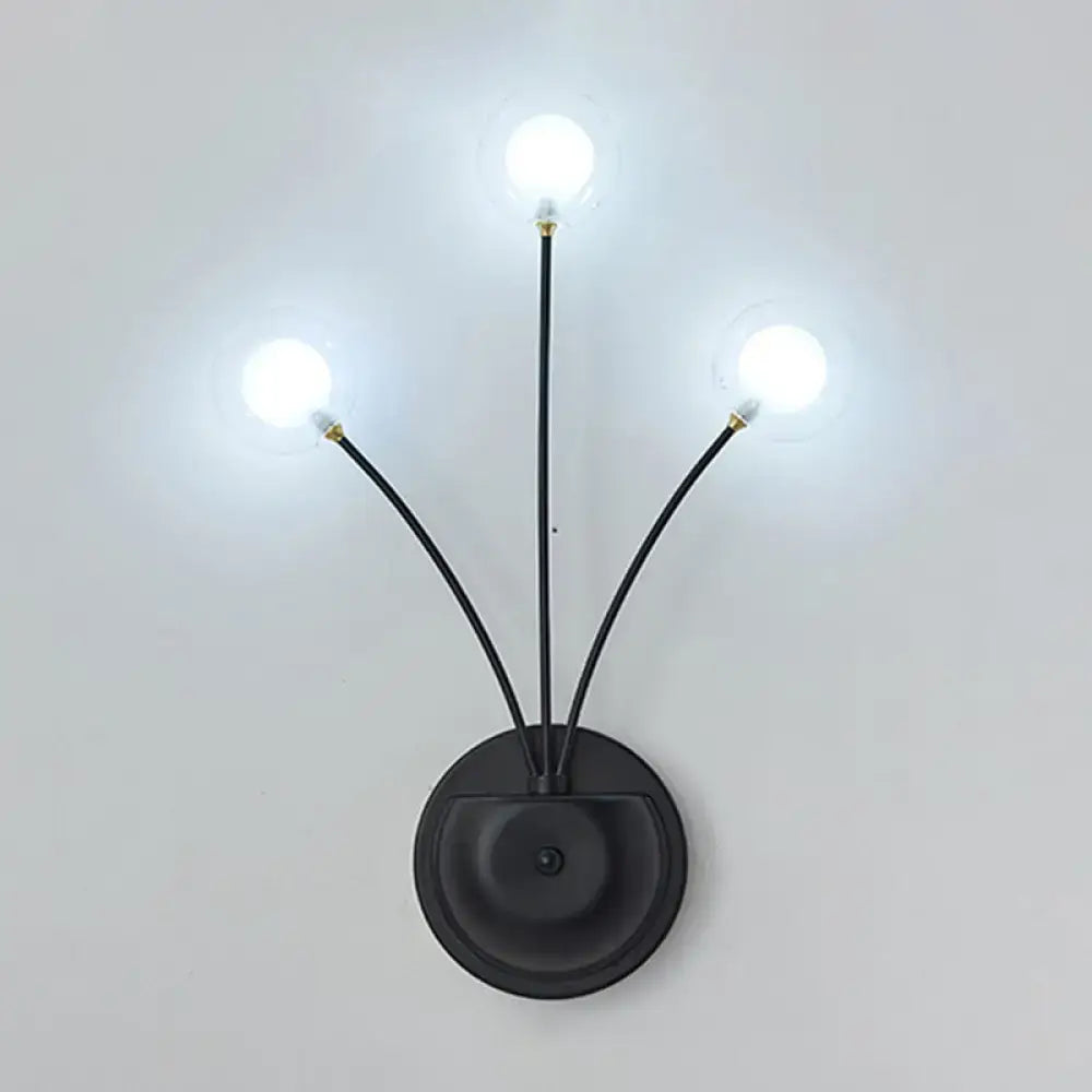 Modern black cast iron three-light wall sconce with slender curved arms and frosted globe bulbs for living room use