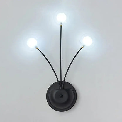 Modern black cast iron three-light wall sconce with slender curved arms and frosted globe bulbs for living room use