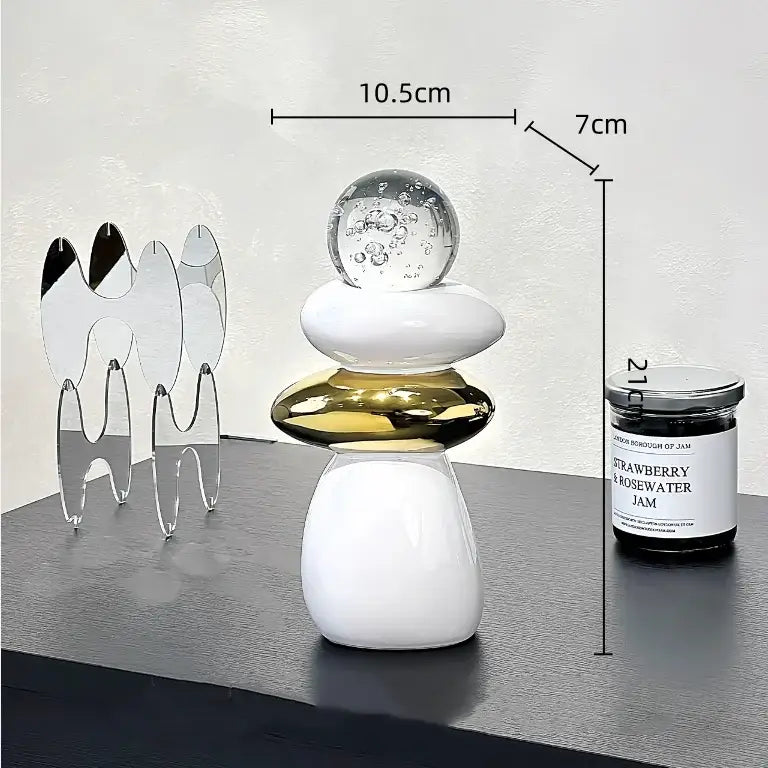 A modern black ceramic decorative crystal ball statue with stacked white and gold discs topped by a bubble glass orb