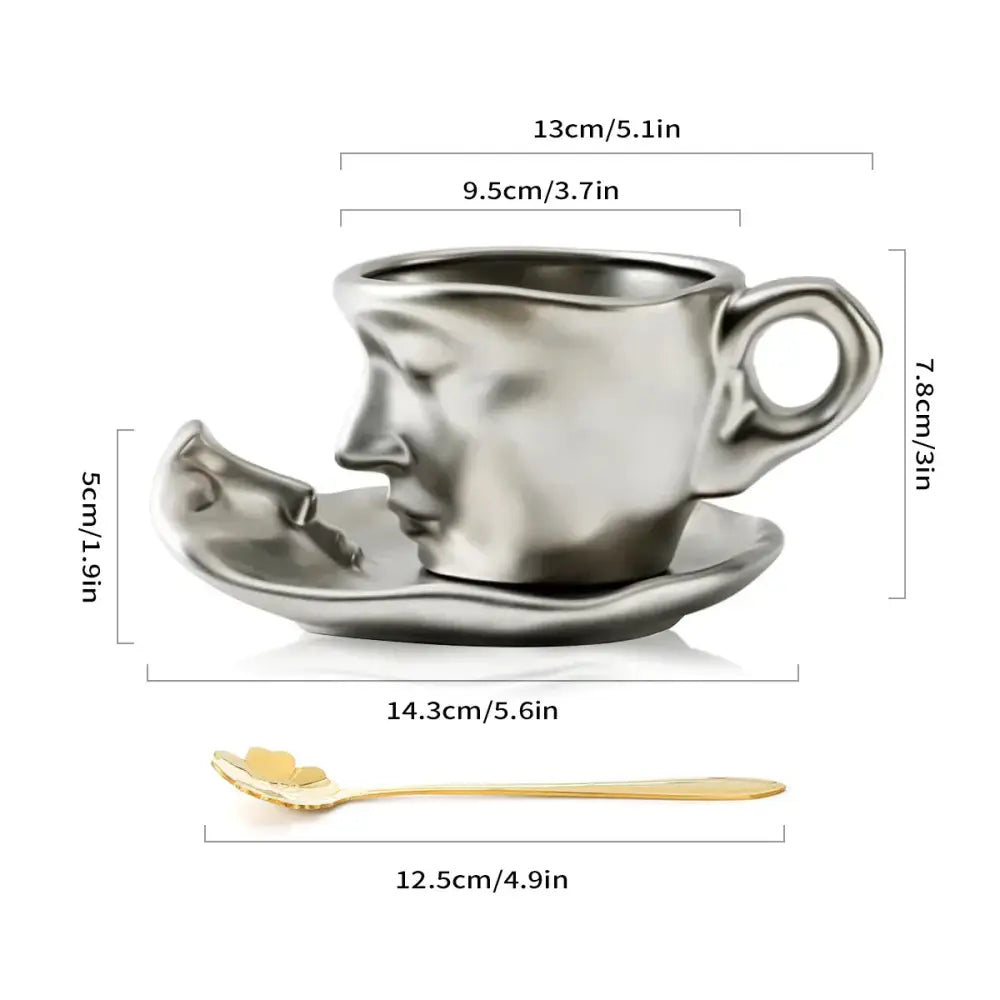 Silver face-shaped ceramic tea cup set with matching saucer and gold-colored spoon for modern dining room use