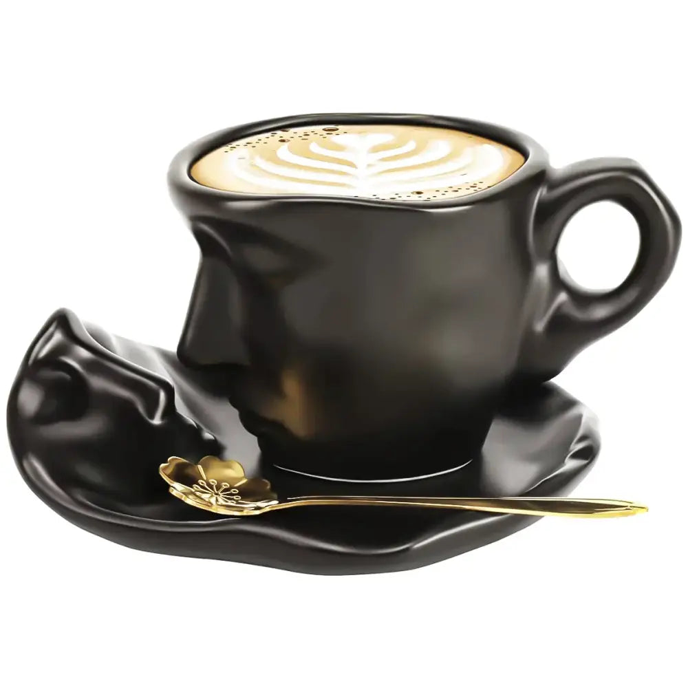 Modern black ceramic tea cup set with kissing face design, matching saucer, and gold leaf-patterned spoon for dining room