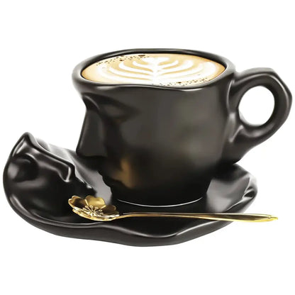Modern black ceramic tea cup set with kissing face design, matching saucer, and gold leaf-patterned spoon for dining room