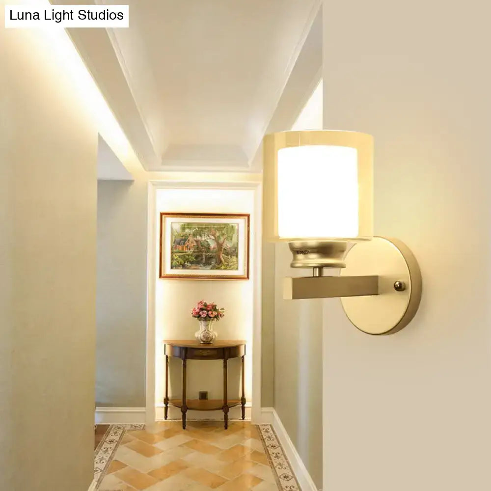 Modern black and chrome wall mounted light with warm-toned brass clear glass sconce and cylindrical frosted shade