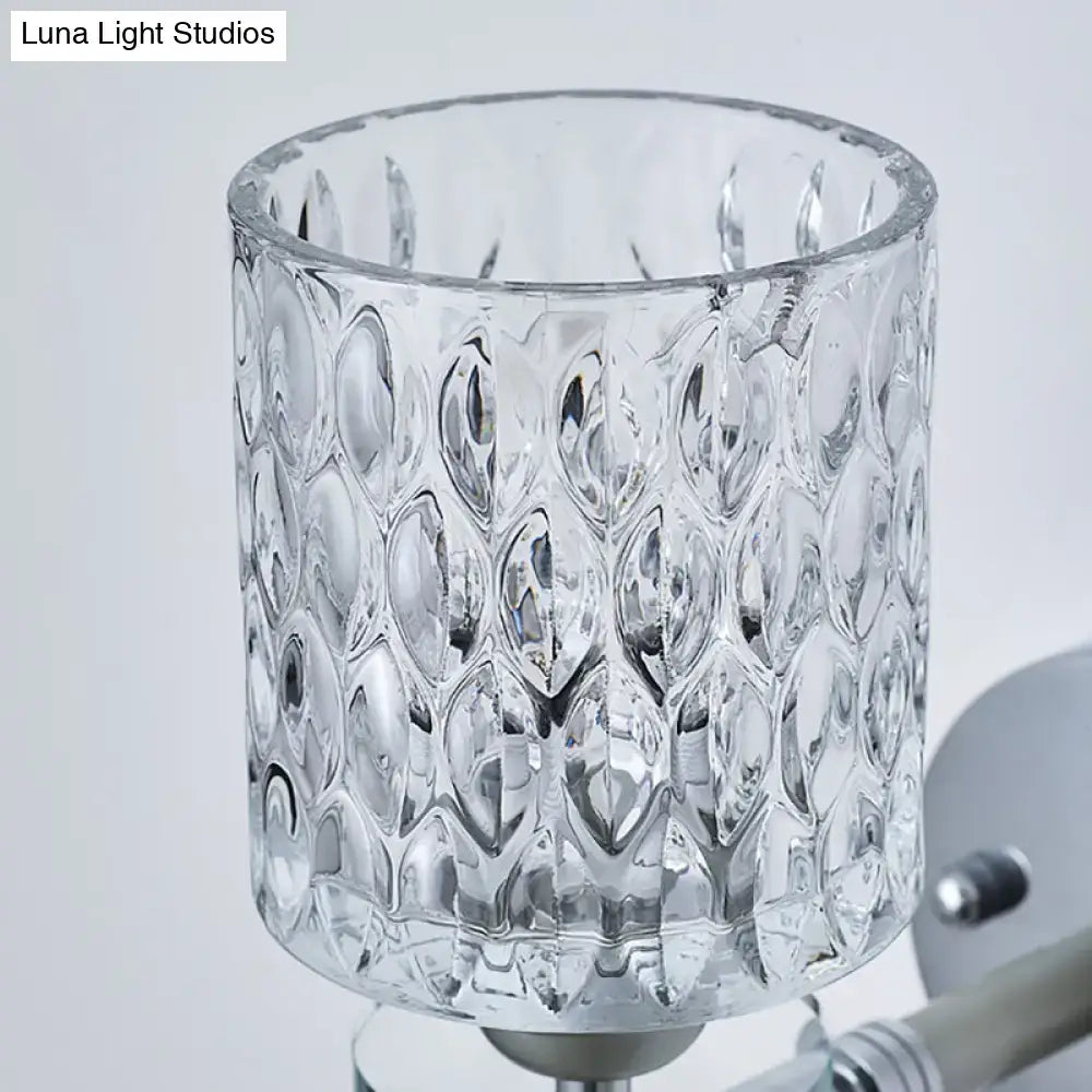 Modern black and chrome wall sconce with dimpled glass cylinder lampshade featuring a textured faceted teardrop pattern