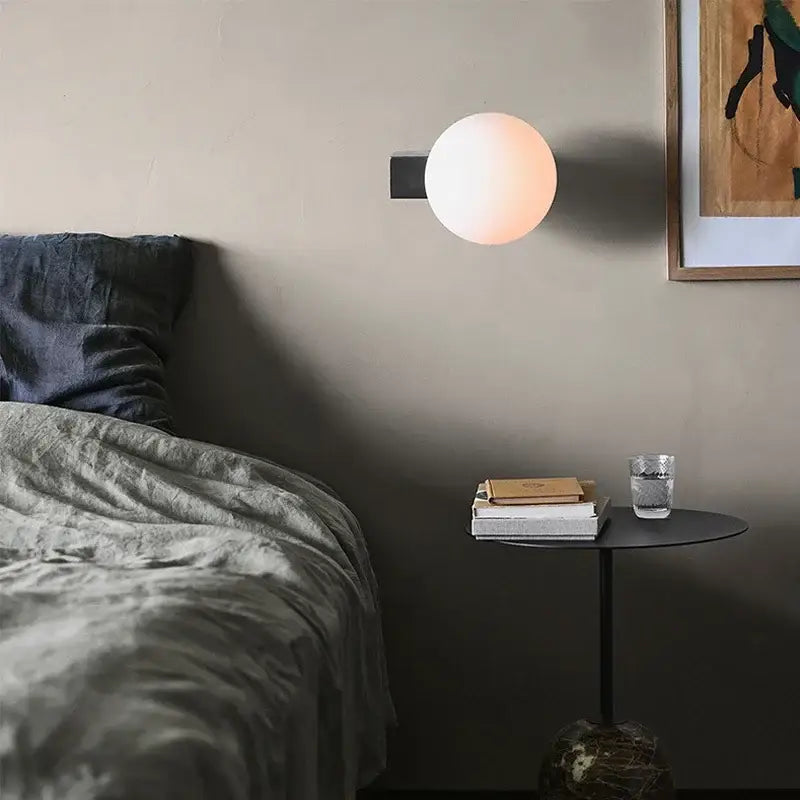 Modern black and chrome decorbites glass ball wall sconce with warm glow and matte black base for bedroom lighting