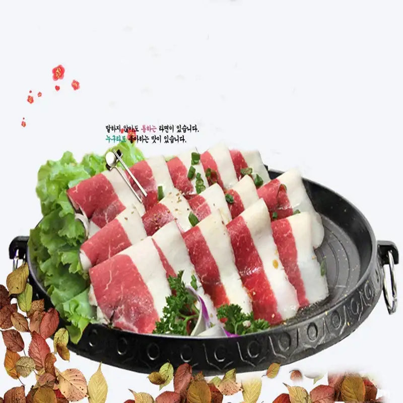 Modern black circular korean grill pan made of cast iron with beef strips and herbs for decorbites korean grill use