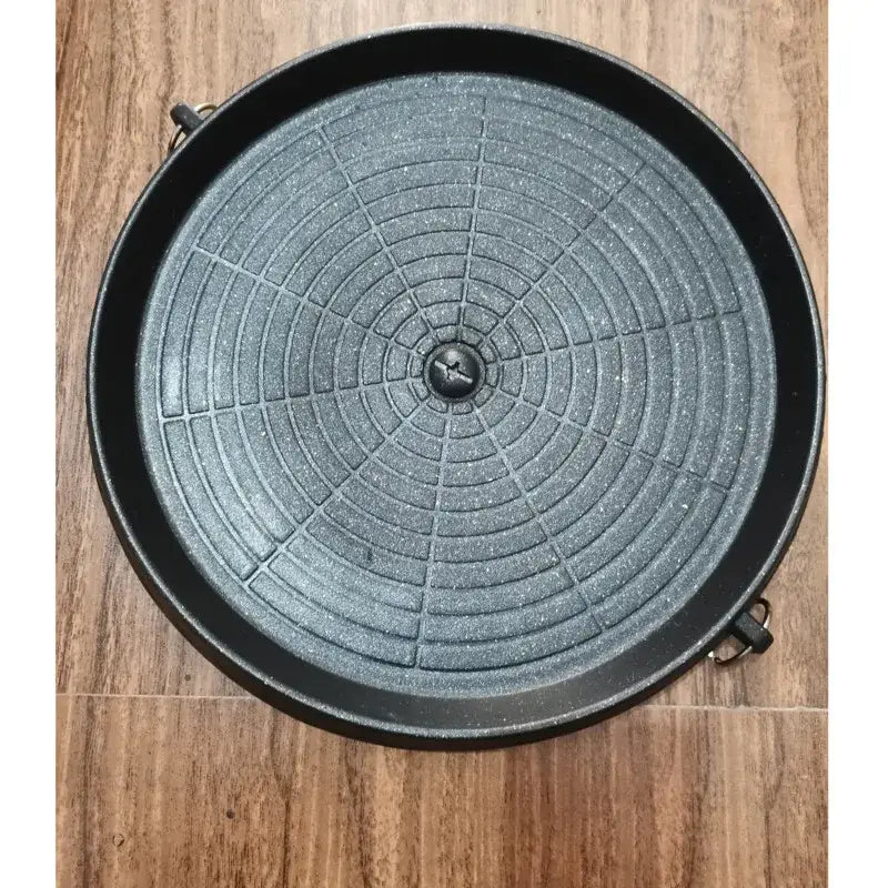 Modern black circular korean grill pan with textured concentric grid pattern and two side handles for kitchen bbq use