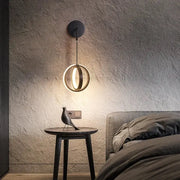 Modern black circular wall sconce light featuring a glowing ring light ideal for bedroom wall sconce lighting