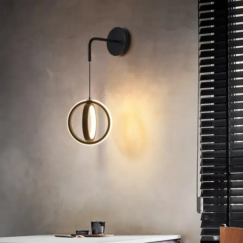 Modern black circular wall sconce light with a glowing ring design emitting warm light for bedroom use