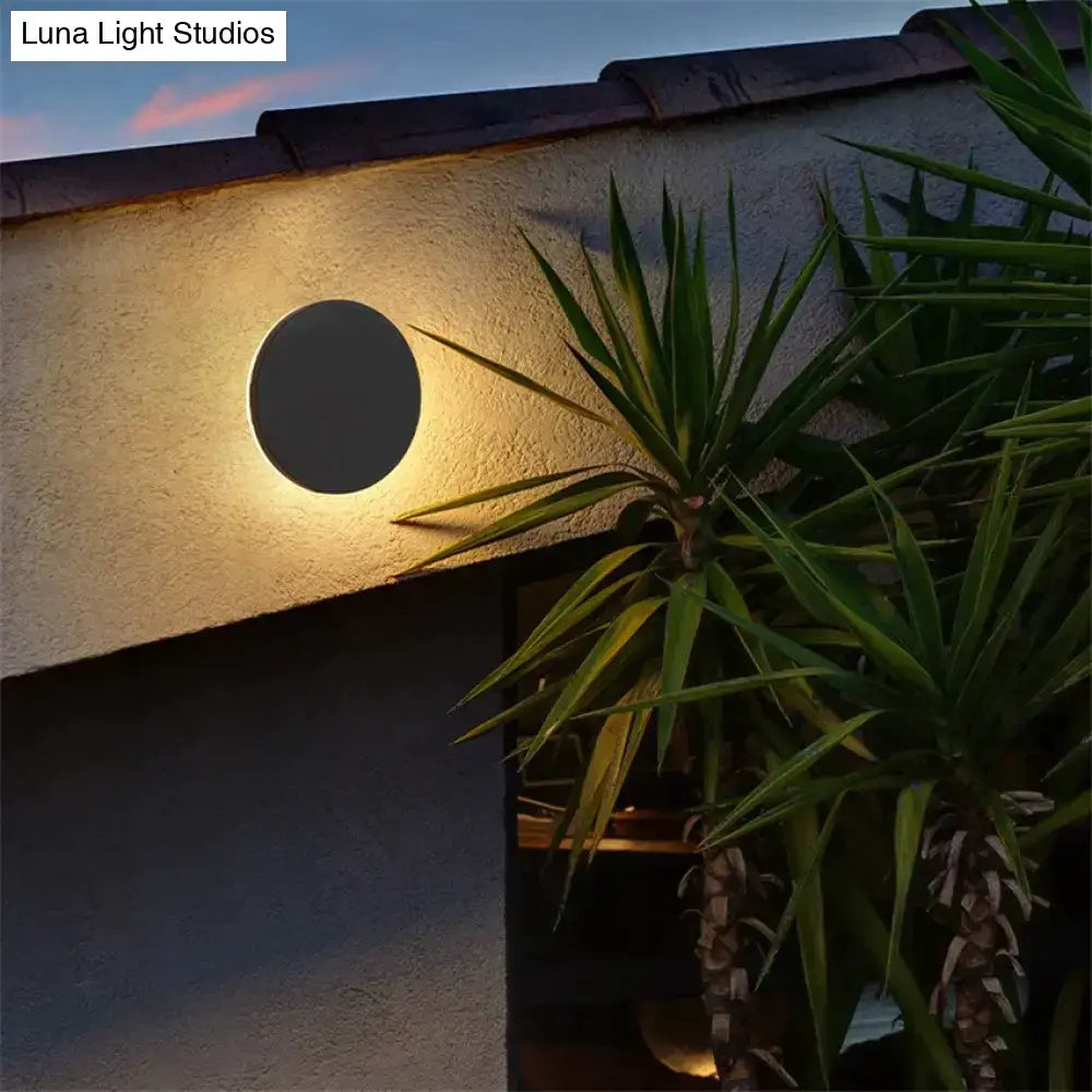 Modern black circular wall lamp emitting a warm glow mounted on a wall for bedroom use