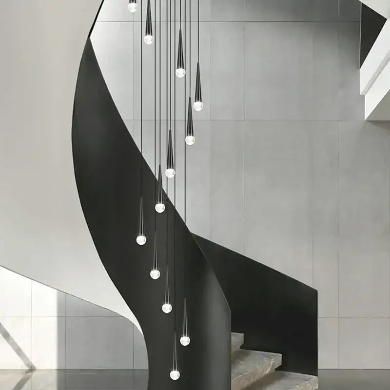 Modern black metal spiral staircase with sleek curved steps illuminated by decorbites crystal led chandelier light