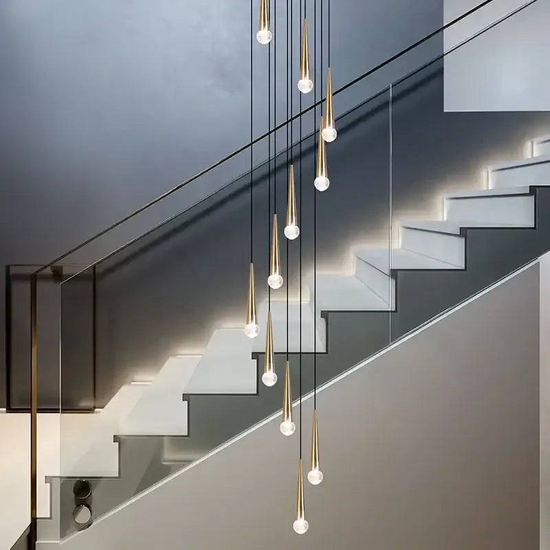 Modern gold-toned decorbites crystal led pendant lights with clear glass globes cascade above staircase