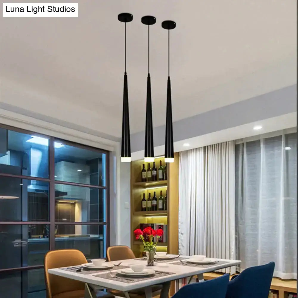 Three sleek black modern led pendant lamps with conical shades hanging over a kitchen island