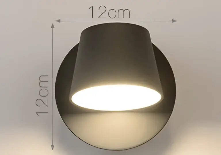 A sleek matte black cylindrical led wall lamp with 12cm diameter emitting warm white light for bedroom reading