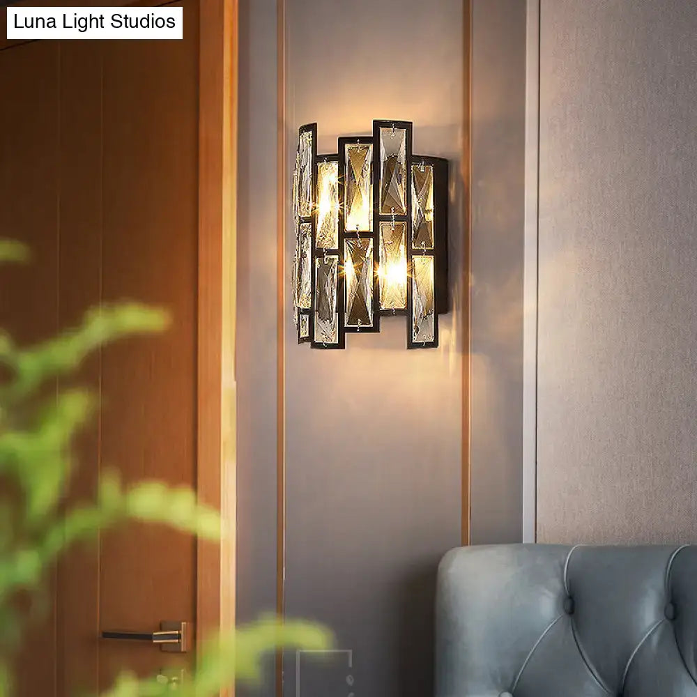 Modern black crystal half cylinder wall lamp with faceted clear crystal panels emitting warm ambient light