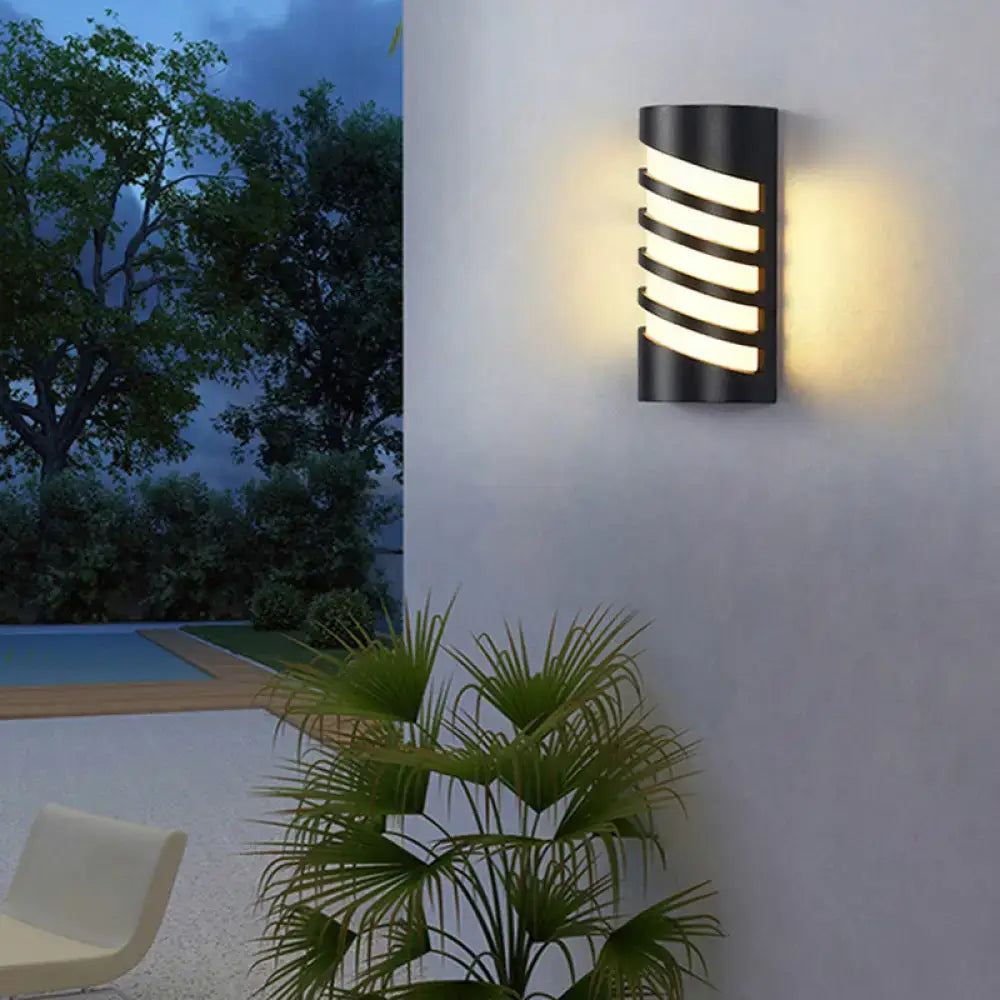 Modern black curved outdoor wall sconce with horizontal slats emitting warm light for patio led lighting