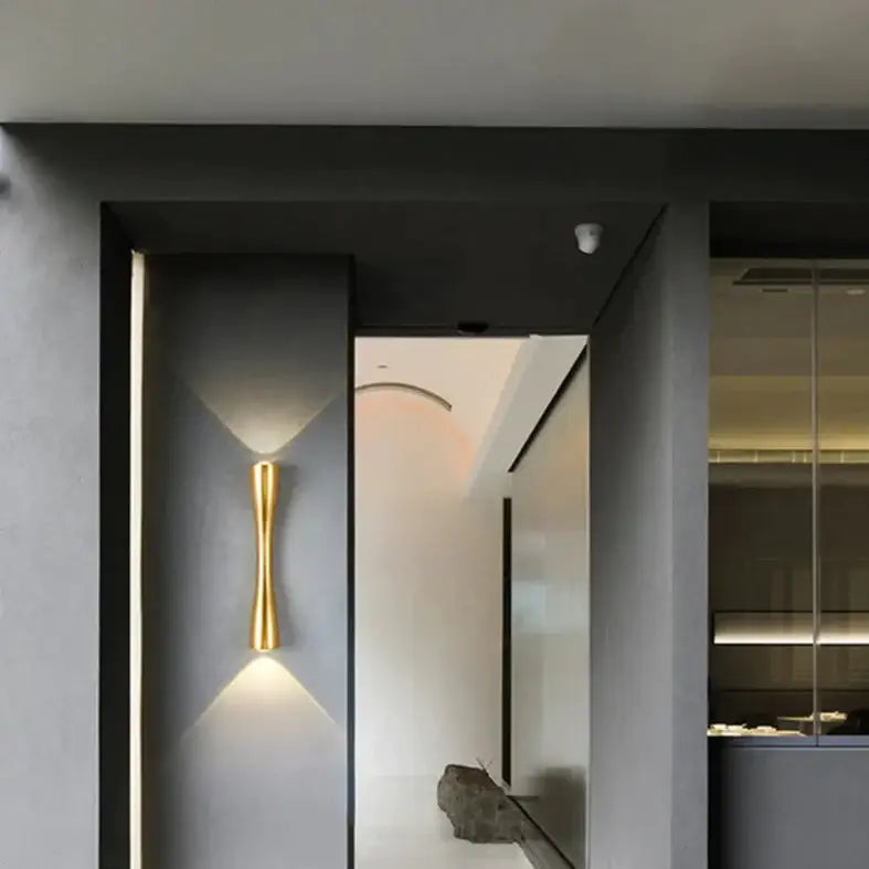 Gold-toned sleekly curved modern wall sconce designed as an outdoor waterproof porch light
