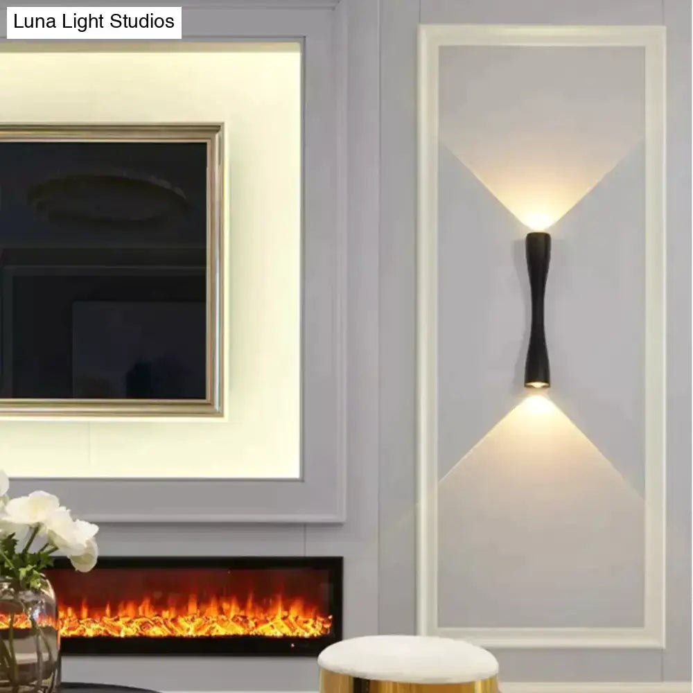 Modern black curved wall sconce with sleek elongated design casting warm light beams for outdoor porch use