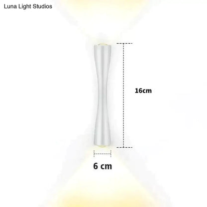 A sleek white led wall sconce with a modern hourglass shape and metallic finish for outdoor porch lighting