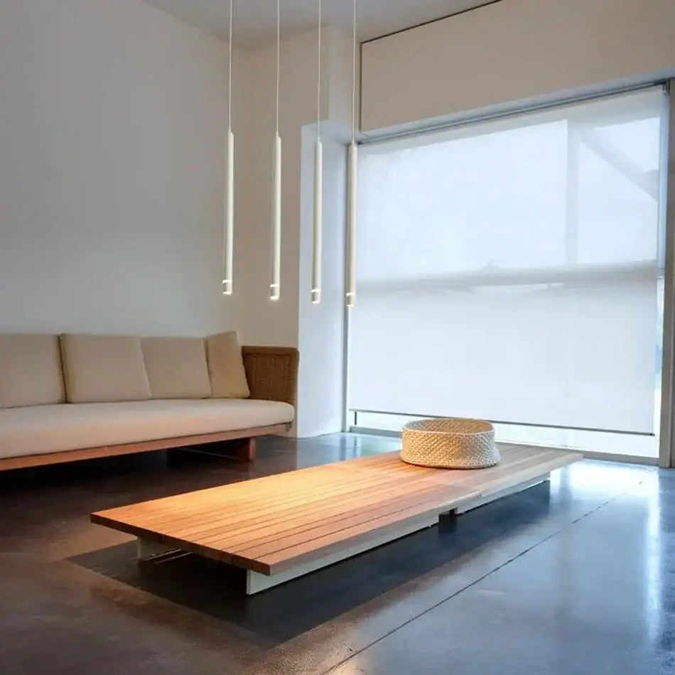 Woven beige basket on a minimalist wooden platform table under modern black decorbites cylinder pipe pendant light