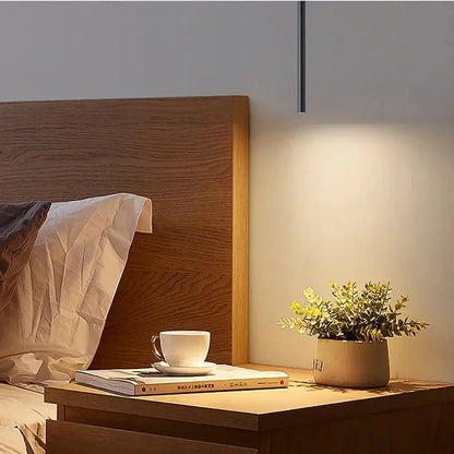 Modern black cylindrical cord pendant light with slender black finish stem and warm focused lighting for bedroom