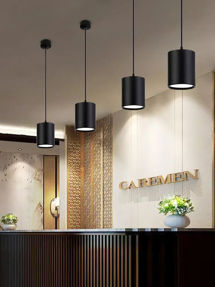 Modern black cylindrical pendant ceiling spot lights with sleek design hanging in kitchen space