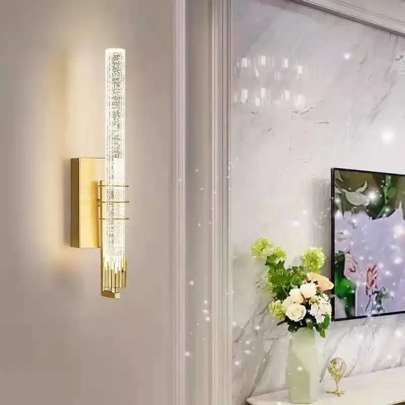 Gold-toned decorbites crystal wall led sconce with clear cylindrical crystal-encrusted light tube and metallic base