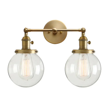 Brass-finished modern wall sconce with double ball heads globe glass shades and vintage edison bulbs for bedroom lighting