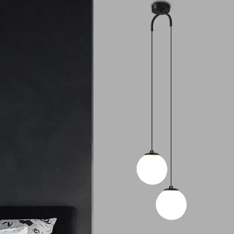 Modern black double glass ball pendant light featuring two frosted glass globes on a curved arm for bedroom ceiling