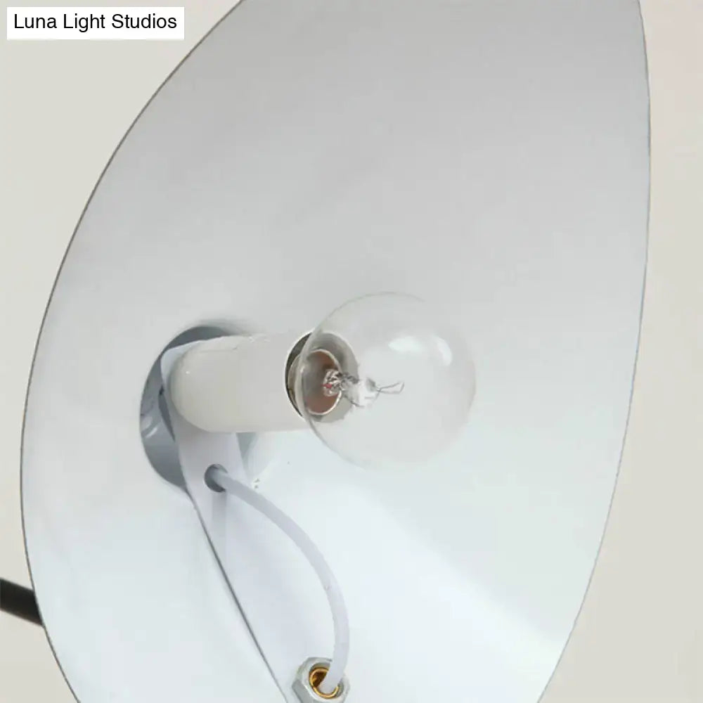 A clear glass bulb with visible filament in a white ceramic socket within a modern black duckbill shade wall lamp with curved arm
