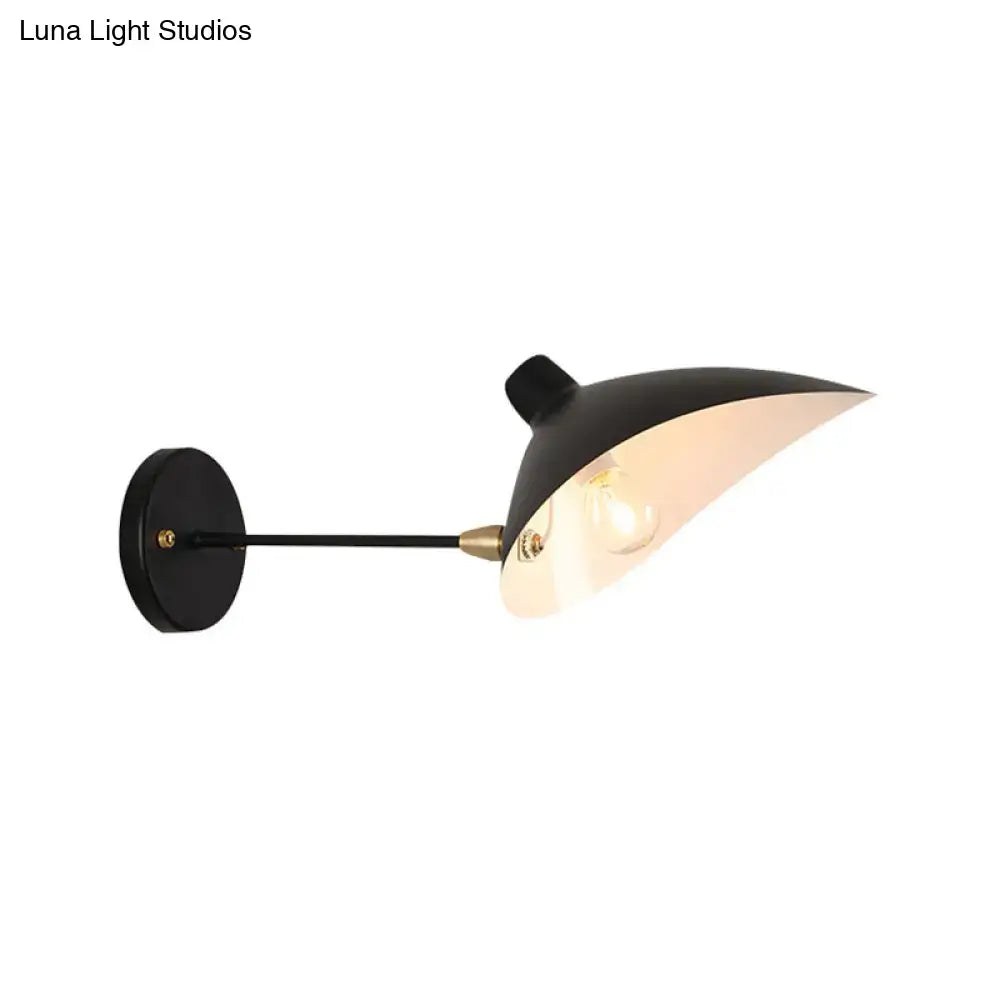 Modern black wall lamp with brass curved arm and sleek angular duckbill shade for bedroom sconce lighting
