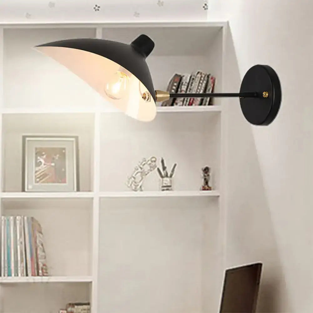 Modern black wall lamp with duckbill shade brass accents and curved arm bedroom sconce mounted on wall