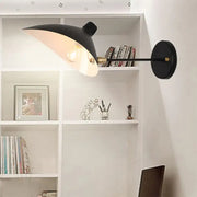 Modern black wall lamp with duckbill shade brass accents and curved arm bedroom sconce mounted on wall