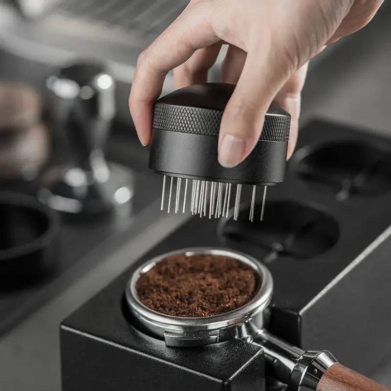 Modern black espresso needle distributor with textured grip and fine metal prongs for precise coffee grounds handling