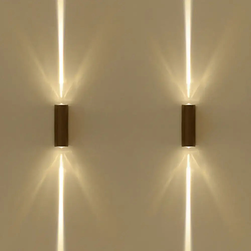 Two sleek modern wall lamps with a black matte finish emit warm dual vertical beams of light for hotel ambiance