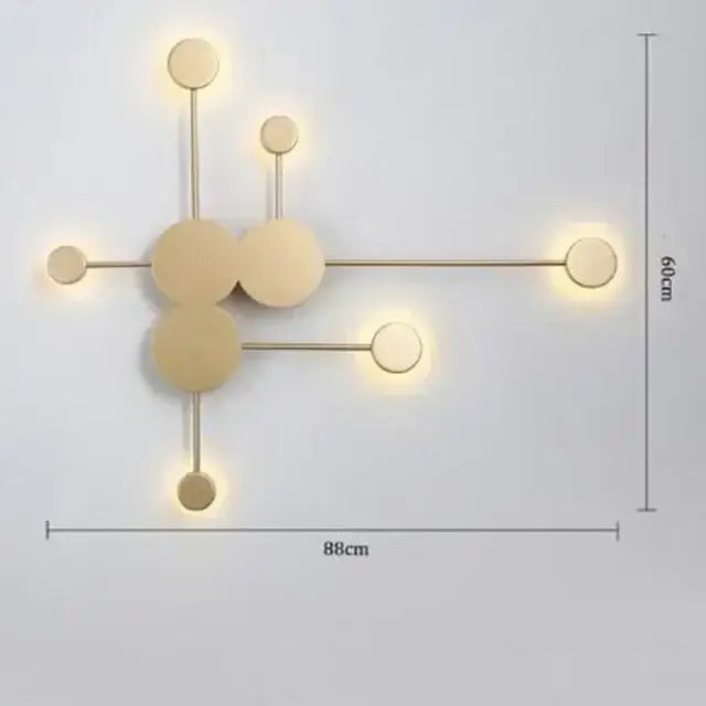 Modern gold-toned wall lamp with geometric interconnected circular design and warm ambient led lighting for bedroom minimalism