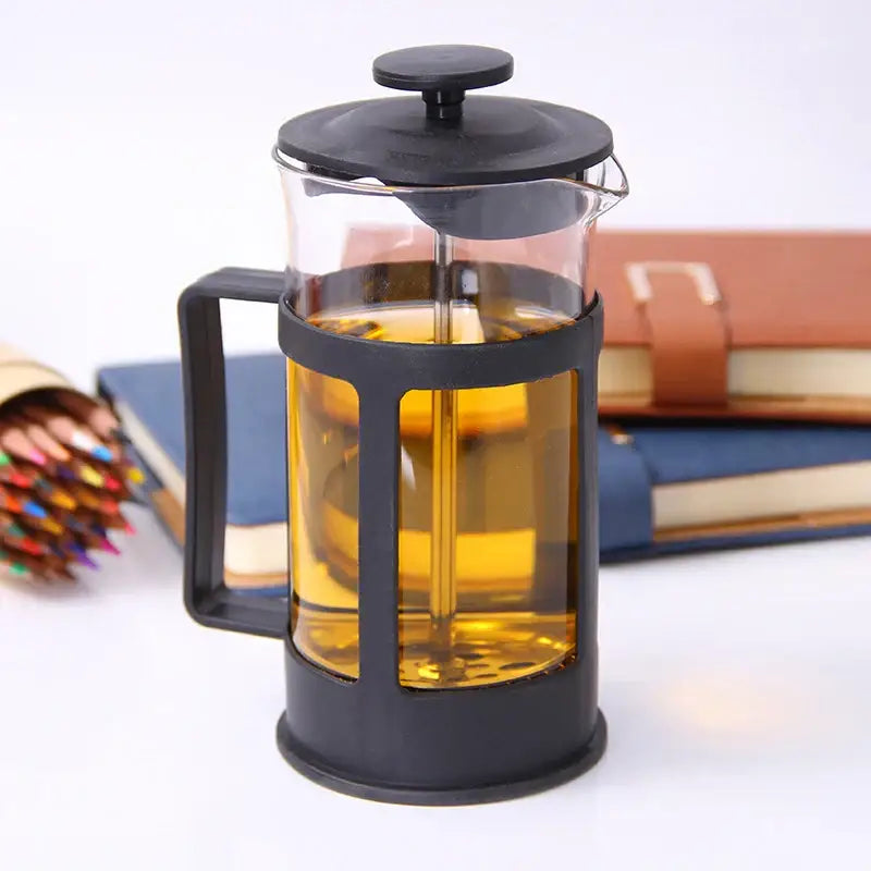 Modern black glass 350ml plastic coffee french press with black frame filled with golden brown brewed tea