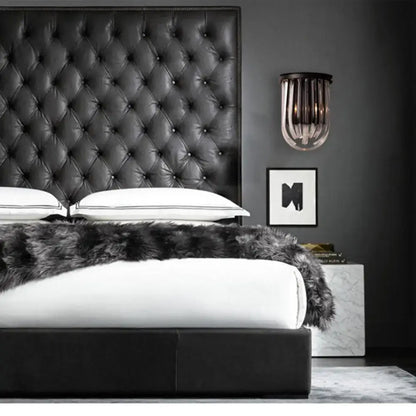 Modern black glass and metal semi oval wall light with black finish mounted above a black tufted leather headboard with diamond pattern stitching