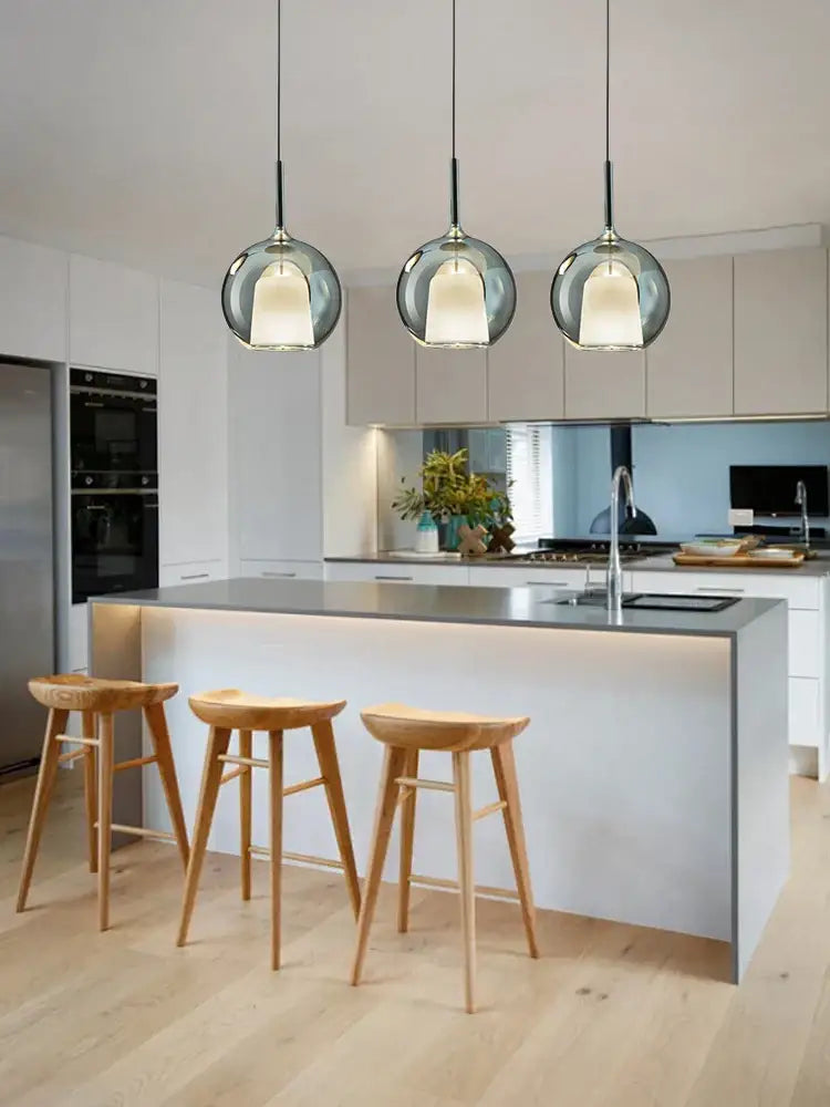 Three modern black glass ball pendant lights with frosted globes hang above a kitchen island decorbites glass ball design