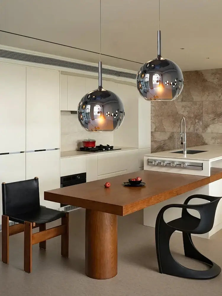 Two spherical chrome glass ball pendant lights hanging above a wooden dining table for modern kitchen island decorbites pendant lights