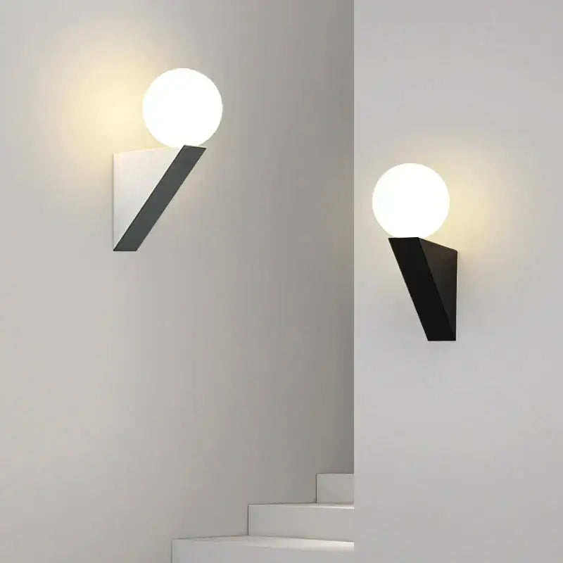 Modern black wall sconce with a glass ball frosted bulb on a sleek triangular metal wall lamp base for bedroom use