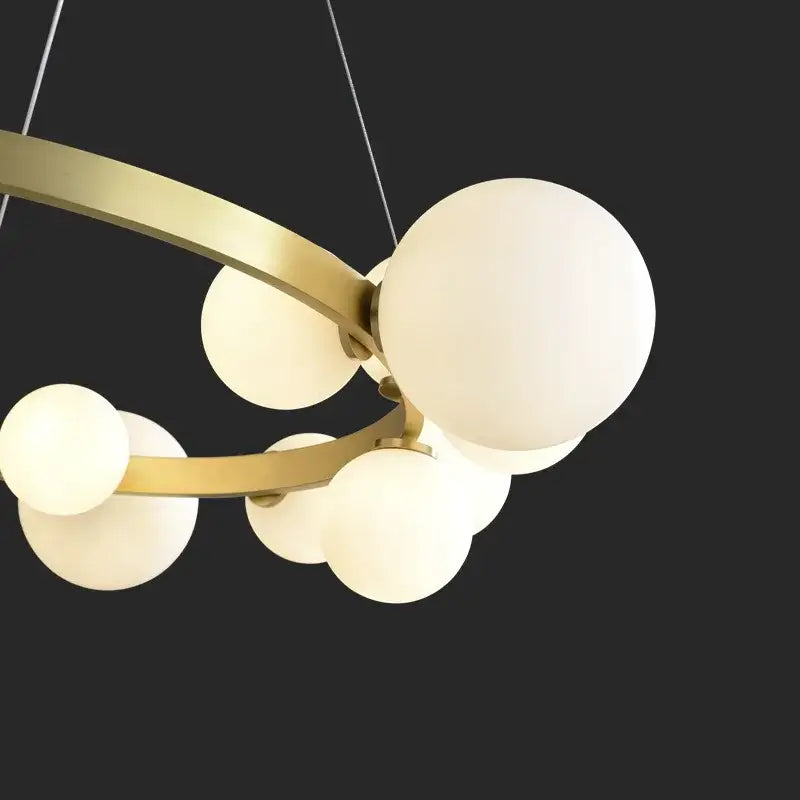 Modern brass-toned pendant light fixture with multiple frosted glass globe shades for dining room use