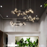 Modern black glass globe pendant light fixture with black metal rings and hanging wires for dining room lighting